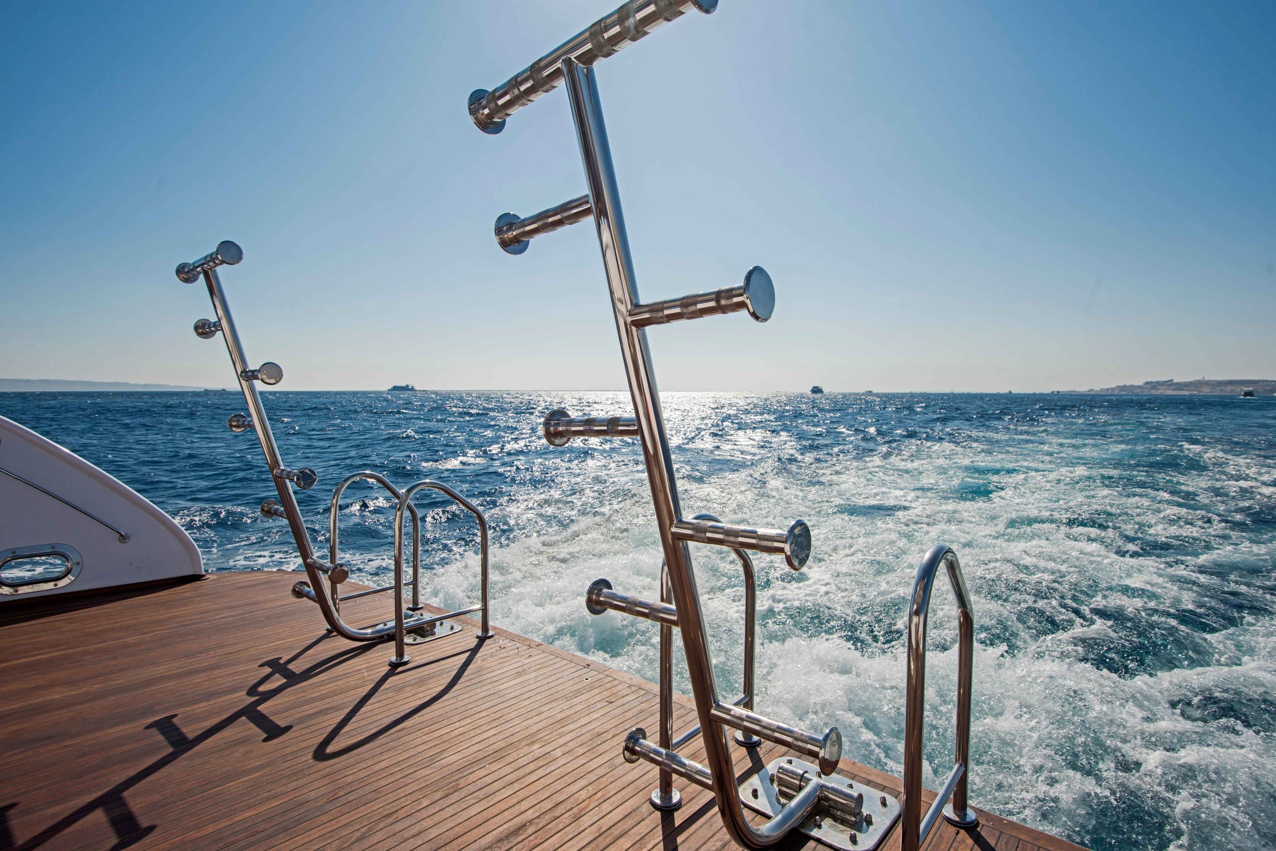 Ladders on the back of a luxury yacht with sea and sky in the background.